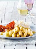 Close-up of asparagus with orange hollandaise and ham crisps on plate