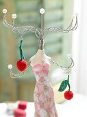 Close-up of crochet patterned earrings in the form of cherries hanging on silver stand