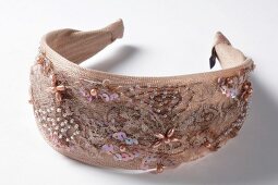 Close-up of beige hairband with sequins on white background
