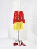 Red silk blouse and yellow skirt on clothes stand