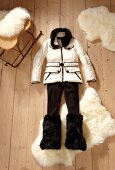 White down jacket, pants and faux fur boots on wooden floor