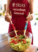 Midsection of woman tossing vegetable pasta