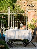 Oak dining table with chairs and cutlery outside Tuscan country house