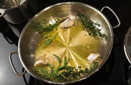Fresh herbs, butter and olive oil in pan for preparation of veal