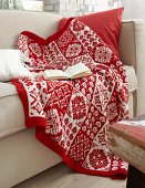 Red and white knitted blanket on sofa with book
