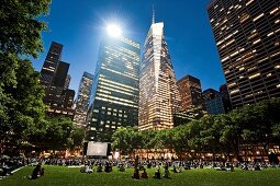 People sitting in meadow and watching movie at Bryant Park, New York, USA