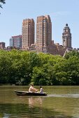 Couple on boat at Central park lake overlooking The Dakota, New York, USA