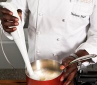 Close-up of man's hand blending apple foam in pan