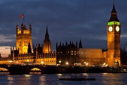 View of illuminated Palace of Westminster, Big Ben and river Thames, London, UK