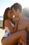 Man embracing woman and looking at her affectionately on beach