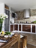 Mediterranean style kitchen with wooden table, cabinet and stone wall