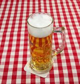 Beer in beer mug on red and white checked napkin