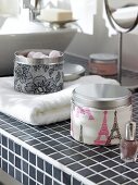 Tins and nail polish on black and white tiled surface in bathroom