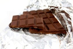 Close-up of chocolate with broken piece on silver paper