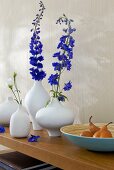 Variety of white vases with purple flowers on wooden surface