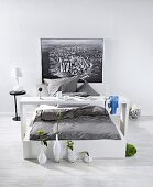 White bed with gray bed sheet, pillows and vase