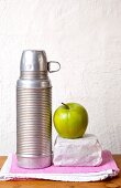 Thermos, apple green and bread wrapped in paper