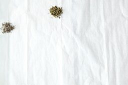 Various herbs and spices on white paper, overhead view