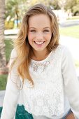 Portrait of pretty blonde woman wearing white lace top, smiling