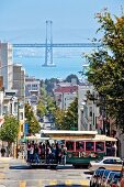 People travelling in tram and Bay bridge in background at San Francisco, California, US