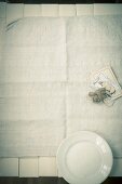 Plate, string, paper and cards on tablecloth, overhead view