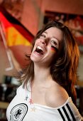 Beautiful brunette woman wearing white German jersey and flag painted on cheek, laughing