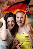 Portrait of two ecstatic women at a football game with Germany flag in background