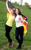 Portrait of two beautiful woman holding Germany flag behind them