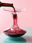 Red wine from decanter being poured in carafe