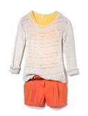 Close-up of white chunky knit sweater and orange shorts on white background