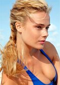 Blond woman with long braided hair in a blue swimsuit