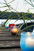 Tealight holders of various colours on lakeside jetty