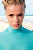 Woman in a green wetsuit looks at the camera, front on