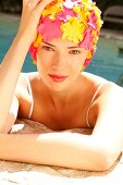 A woman wearing makeup with a colorful bathing cap looking into the camera