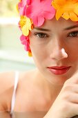 A woman wearing makeup with a colorful bathing cap looking into the camera