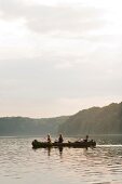 Three people sailing canoe in Breiter Luzin lake, Mecklenburg, Germany