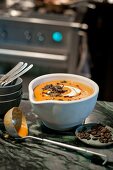 Pumpkin soup garnished with curry, cinnamon, coconut milk, roasted pumpkin seeds in bowl
