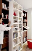 Woman moving white wooden shelf, blurred motion