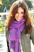 Portrait of attractive woman wearing green jacket and purple scarf, smiling