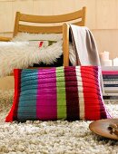 Colourful knitted cushion with stripes against wooden chair