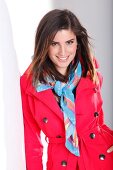 Portrait of attractive dark haired woman in red trench coat and colourful scarf, smiling