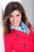 Portrait of attractive dark haired woman in red trench coat and colourful scarf, smiling