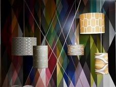 Various illuminated ceiling lamps in front of geometric non woven wallpaper