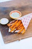 Sweet potato chips in a paper bag with herb sauce