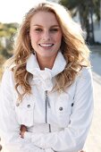 Portrait of pretty blonde woman in jacket with stand-up collar standing with arms crossed