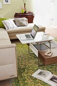 Chaise sofa and coffee table with laptop and coffee cup on green, patterned rug in living room