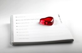 Red glass heart on calendar with date of 14th February