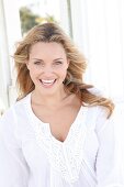 Portrait of happy woman wearing white tunic blouse, smiling