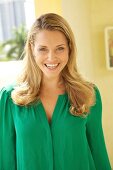 Portrait of happy blonde woman wearing green blouse, smiling