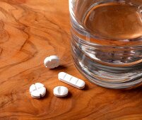 Close-up of tablets and glass of water on wooden table